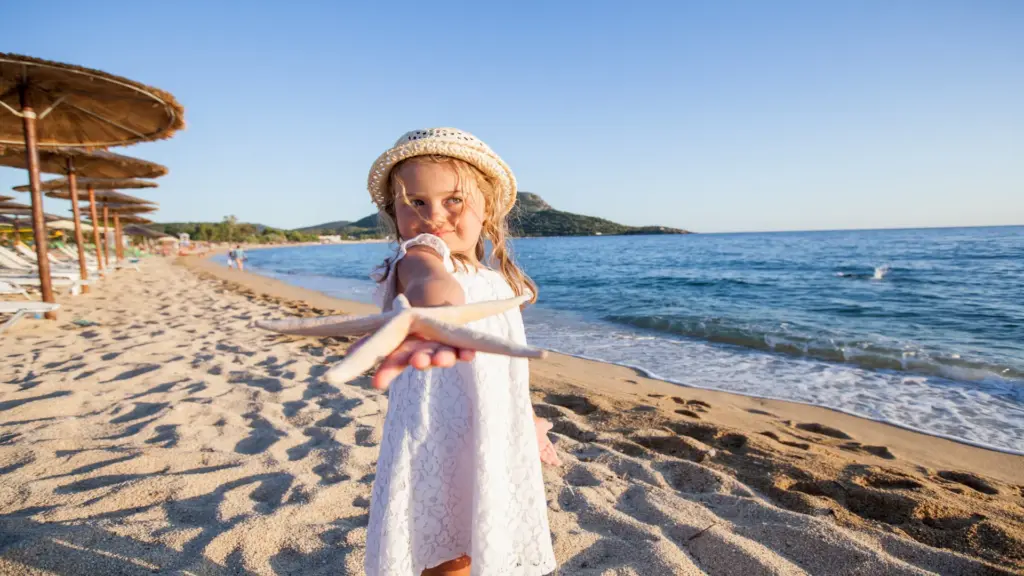 Mädchen spielt am Strand mit Seestern